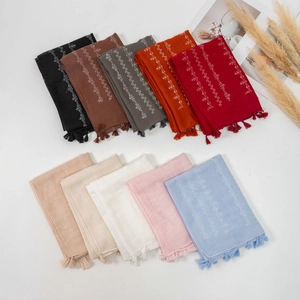 Flat lay of cotton linen scarves in ten solid colors with white embroidery and tassels
