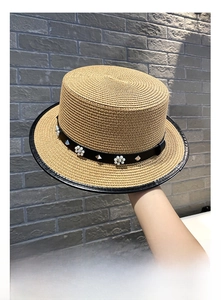 Detail of flat top straw boater hat with leather band, white pearls and silver studs