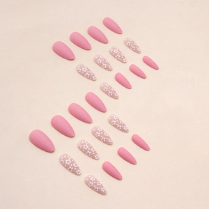 Matte pink almond press-on nails with white polka dots for a sweet minimalist look