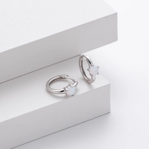 Macro shot of silver S925 sterling silver hoop earrings featuring white opal gemstones