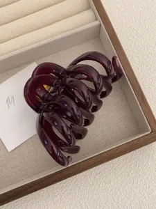 Detail of burgundy large octopus hair claw clip with glossy finish on a wooden tray