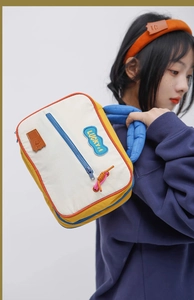 Detail of colorful canvas cosmetic bag with Lucky+1 patch and blue padded strap