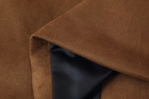 Detail of dark brown faux suede fabric showing smooth texture and contrast lining