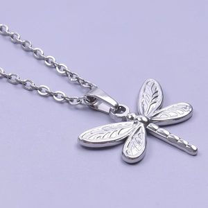Macro shot of silver dragonfly pendant in polished stainless steel on purple background