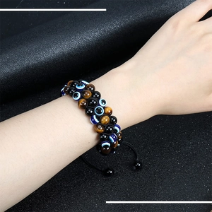 Close-up of triple-layer braided bracelet with 8mm tiger eye beads and evil eye charm