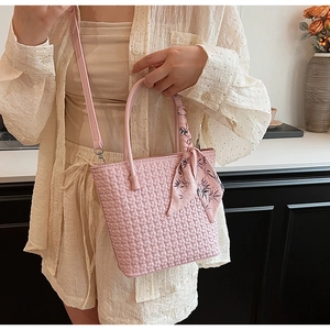 Detailed shot of pink woven bucket bag with silk scarf handle and detachable strap