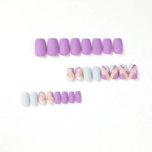 Blue and purple press-on nails with white flower art, gold foil, and geometric designs