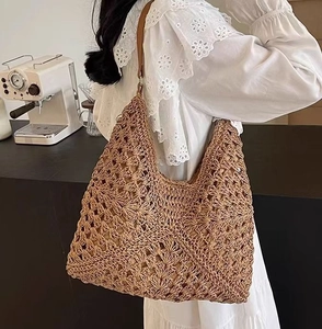 Dettaglio della borsa in paglia intrecciata con tracolla in pelle marrone e trama a vista