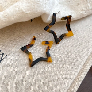 Detail of star-shaped leopard print resin earrings with tortoise shell pattern texture
