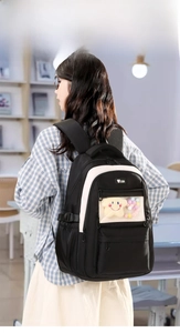 Detail of ergonomic back straps on a black and white nylon backpack with plush charm
