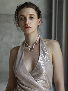 Modella indossa collana con ciondolo sole in oro 18K e abito di paillettes estivo