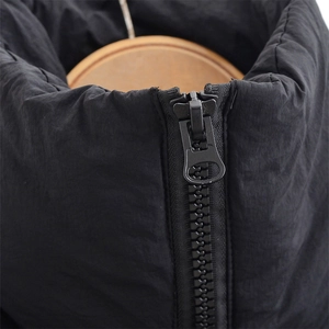 Close-up of a smooth metal zipper on a black padded vest with soft fabric texture