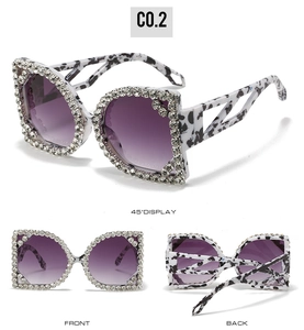 Detail view of oversized cow print sunglasses with sparkling rhinestones and purple lenses