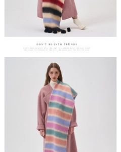 Detailed view of colorful striped scarf with fluffy pom-poms on a pink winter coat