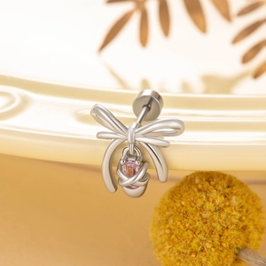 Silver bow stud earrings with pink zircon stone on a decorative ceramic plate
