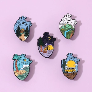 Detailed close-up of five heart-shaped enamel pins featuring unique nature landscape designs