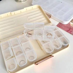 Détail de la boîte à bijoux beige avec poignée or rose et compartiments transparents