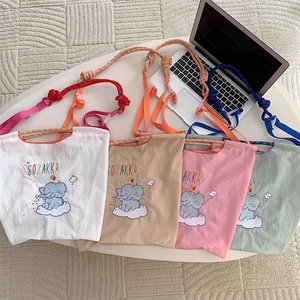 Detail of cute elephant embroidery on four colorful oxford cloth tote bags with rope straps