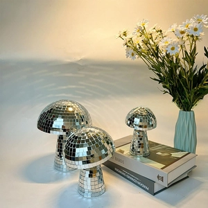 Three reflective silver mirror mushroom disco balls in various sizes on a table