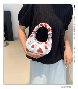Dettaglio borsa in tela con stampa a fragola e design del manico a spalla arricciato