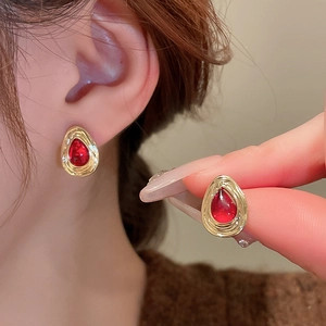 Close-up of vintage teardrop earrings with red tiger eye stone and gold-toned metal textured edge