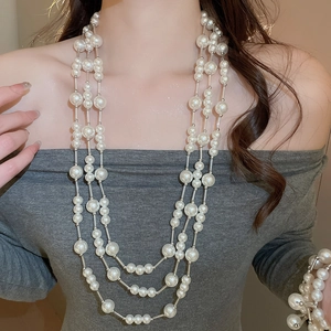 Close-up of elegant layered pearl necklace and silver chain worn by a female model