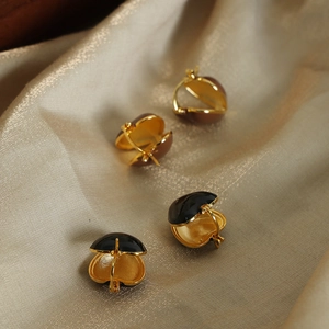 Golden heart-shaped enamel hoop earrings in black and brown on champagne silk