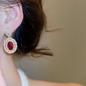 Detail of vintage gold plated earrings with oval red gemstone and zircon accents