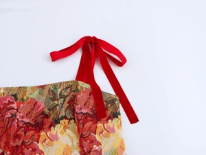 Dettaglio del fiocco in velluto rosso sulla spalla dell'abito floreale vintage jacquard