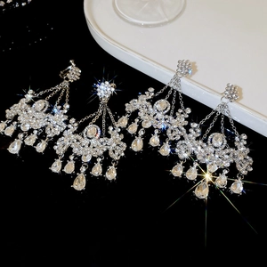 Gros plan sur des boucles d'oreilles fleurs en argent avec pompons et cristaux brillants