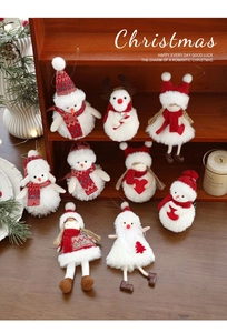 Detailed close-up of plush Christmas ornaments with snowman and doll designs on a wood shelf