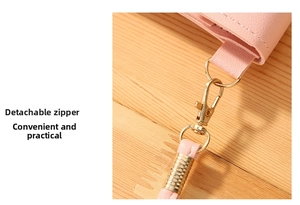 Detail of pink leather bag with detachable golden metal hook buckle on wood background