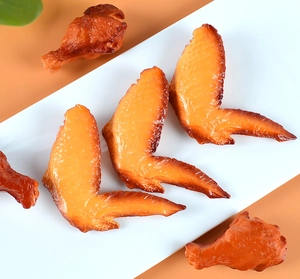 Macro di ali e cosce di pollo arrosto artificiali realistiche su un piatto bianco