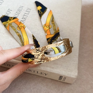 Detail of vintage gold bangle with hammered texture and silk scarf wrap ornament