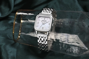 Détail de la montre argentée avec cadran en nacre sur un fond en velours vert
