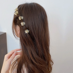 Close-up of small champagne floral hair claw clips worn on wavy hair for styling