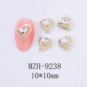 Detailansicht goldener herzförmiger Nagel-Charms mit Strasssteinen und Love-Schriftzug