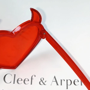 Detail shot of heart-shaped sunglasses with unique devil horns and transparent red frame
