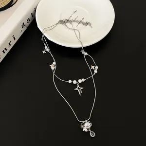 Detail view of silver double-layer necklace with pearl stars and Saturn planet pendant
