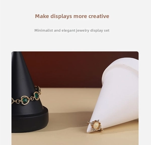 Detail view of black and white matte conical stands displaying gold gemstone jewelry