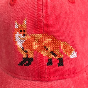 Macro view of high-quality cross-stitch fox embroidery on a red washed cotton baseball cap
