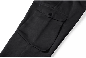 Dettaglio della tasca laterale dei pantaloni cargo neri con patta a bottone e saia fine
