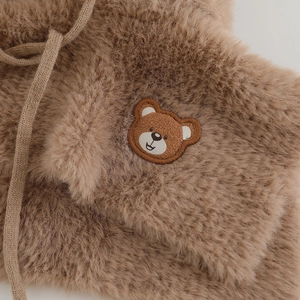 Detail of soft brown faux fur texture with cute bear embroidery and knitted drawstring