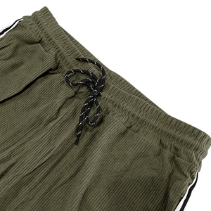 Detail of army green corduroy joggers showing the elastic waistband and striped drawstring
