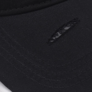 Dettaglio macro della visiera logora di un cappellino da baseball nero in cotone lavato