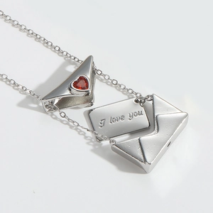 Detailed macro view of silver envelope pendant with red heart and 'I love you' card