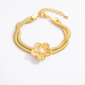 Detail eines goldenen Schlangenarmbandes mit Gänseblümchen-Anhänger und weißer Perle