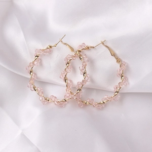 Detailed close-up of pink faceted crystal earrings on a white elegant silk background