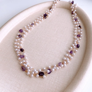 Detail view of double-layer pearl and amethyst beaded necklace on a beige tray