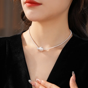 Dettaglio macro dell'elegante collana di perle tonde con accenti in zircone su velluto nero